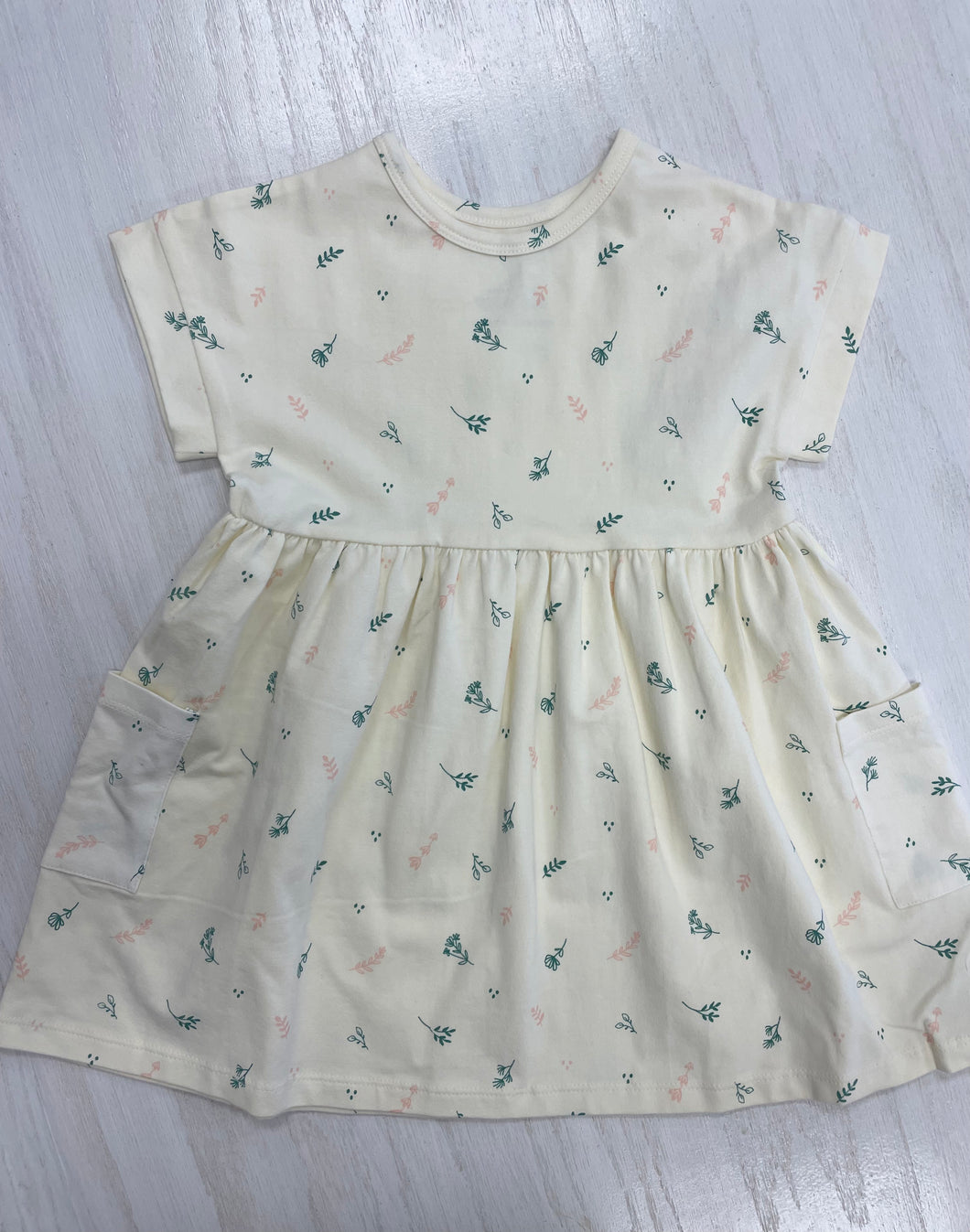 Cream colored girls' dress with quality, breathable cotton and dainty pattern.
